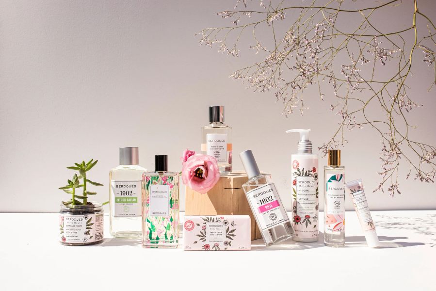 Parfums Berdoues présentés sur une table avec plusieurs flacons de la collection 1902 et soins parfumés dans une ambiance lumineuse et naturelle